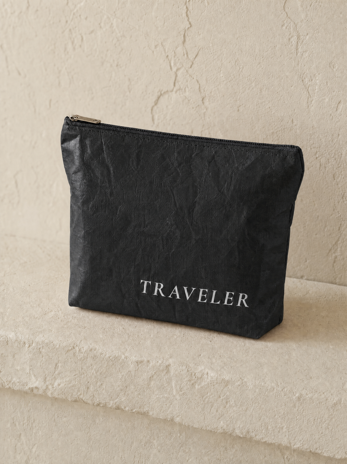 Ink mini water-resistant accessory bag — a soft black 6 x 3.75 inch zip travel pouch in matte crinkled fabric with TRAVELER printed in white