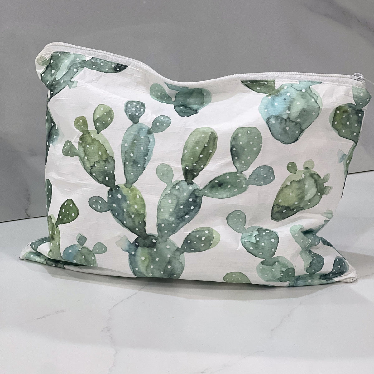 Back of the Cool Cactus Medium flat accessory bag on a white marble counter