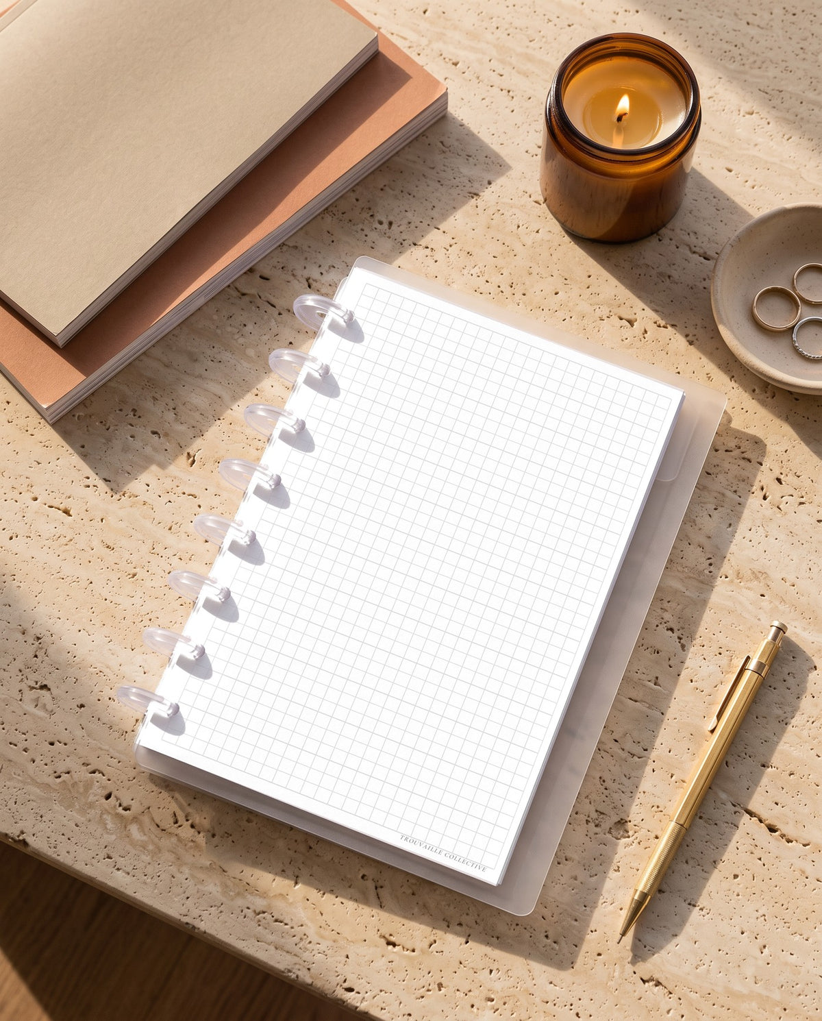 Grid planner insert inside a clear half letter discbound planner with 8 discs on a travertine desk with a candle