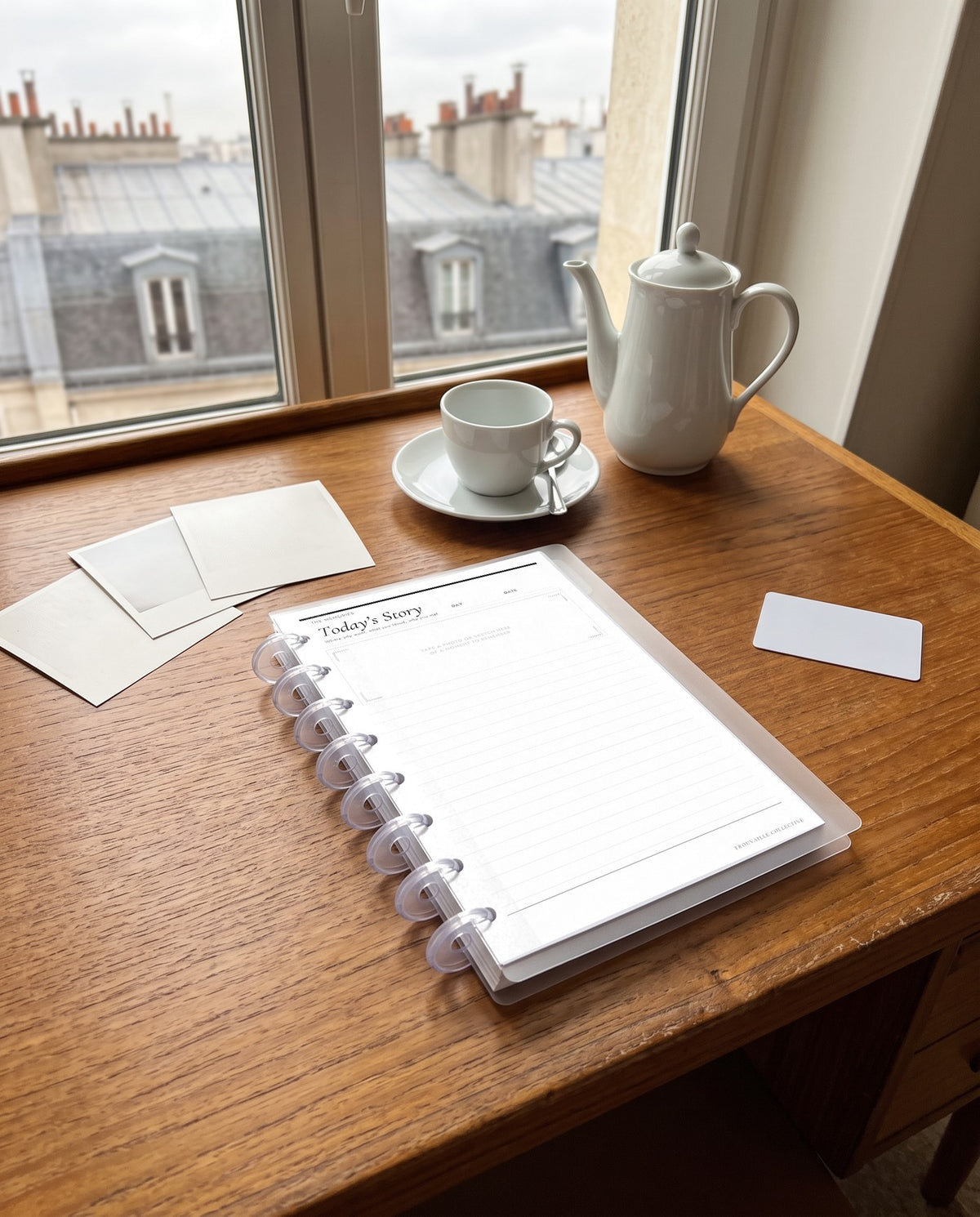 Journal Page planner insert inside a clear half letter discbound planner with 8 discs on a hotel writing desk overlooking Paris rooftops