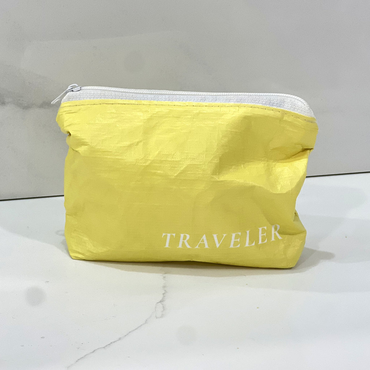 Lemon yellow Mini zip pouch sitting on a white marble counter