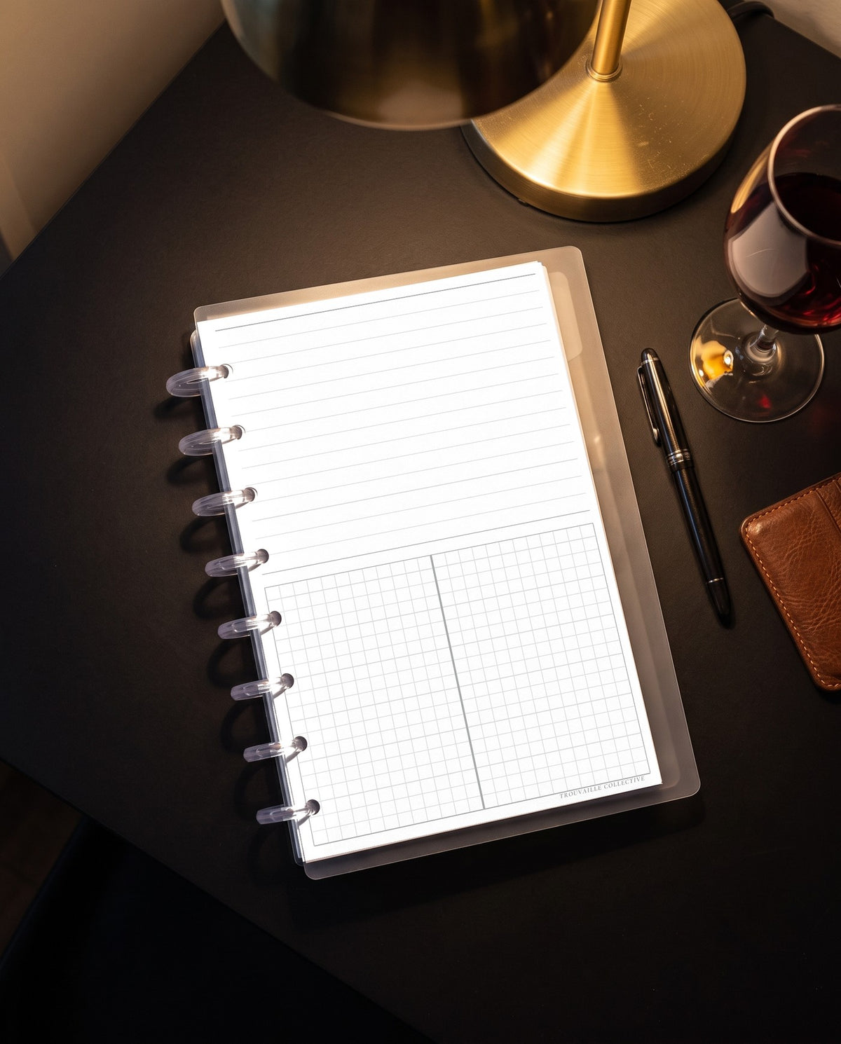Lines + Grid planner insert inside a clear half letter discbound planner with 8 discs on a black desk under a brass lamp