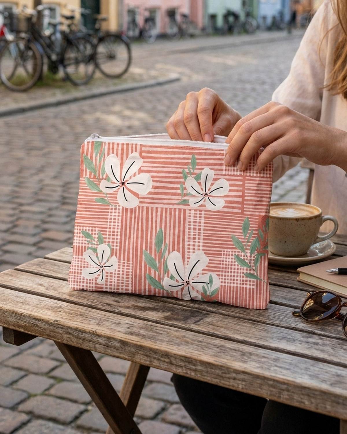 A coral floral water-resistant accessory pouch on a cafe table in Copenhagen