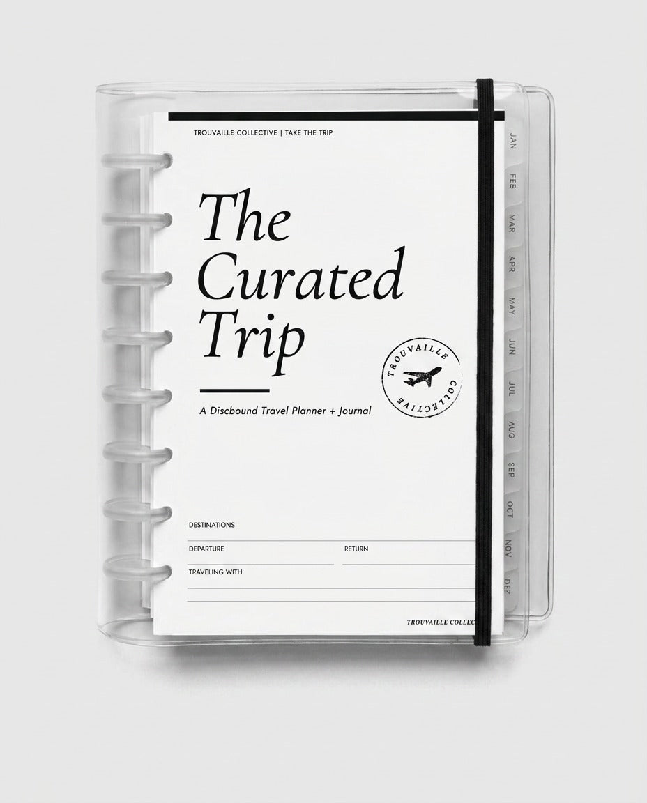 The Curated Trip half letter discbound travel planner journal in a clear cover with elastic closure