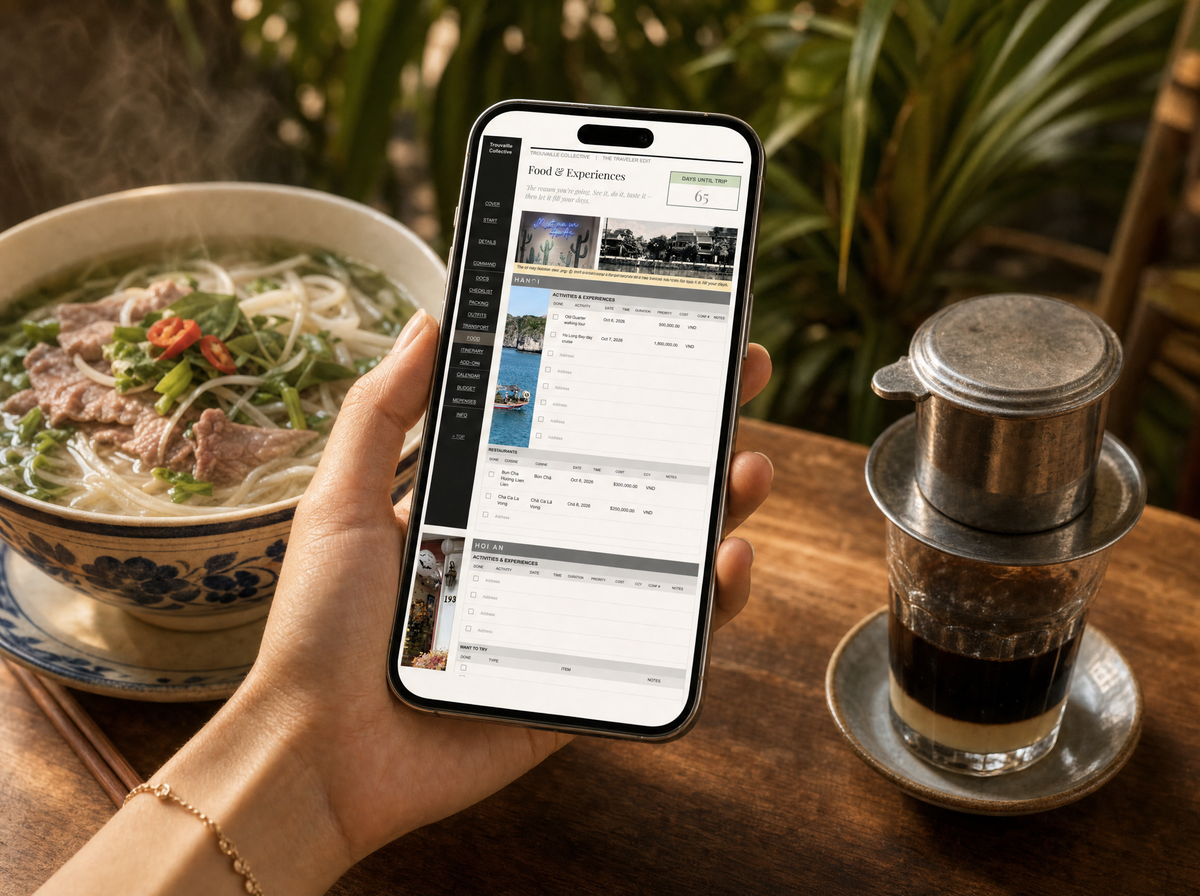 A hand holds an iPhone showing the Traveler Edit Food & Experiences tab over a bowl of Vietnamese pho and phin coffee