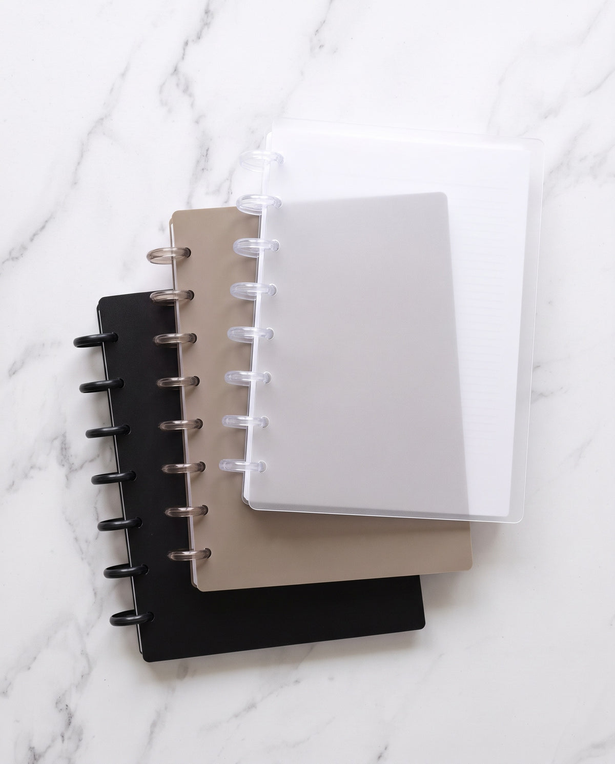 Half letter discbound planners in clear, taupe and black, each with 8 matching discs; the taupe discs are translucent