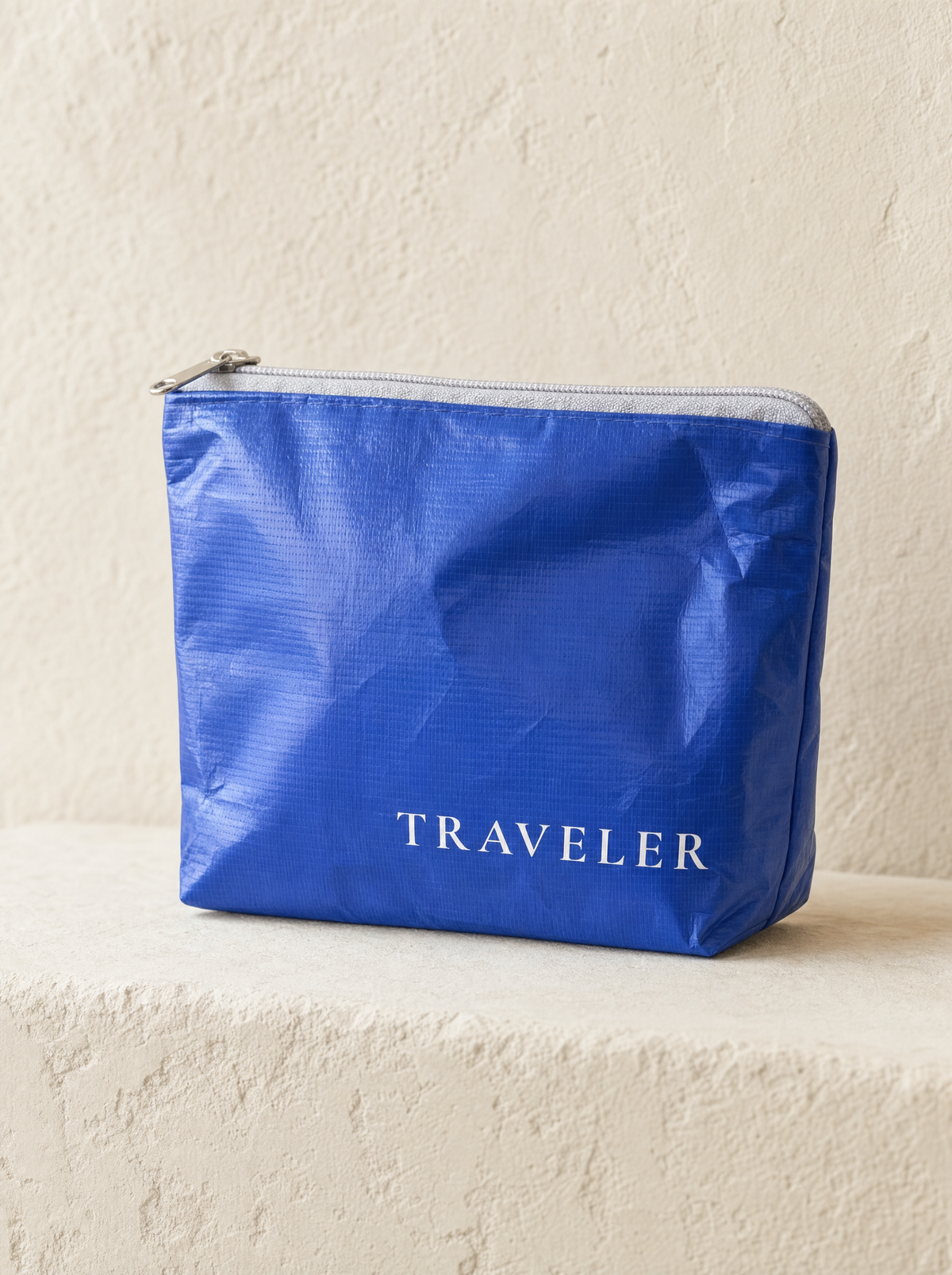 Fresh Water Blue mini water-resistant accessory bag — a solid blue 6 x 3.75 inch zip travel pouch with TRAVELER printed in white
