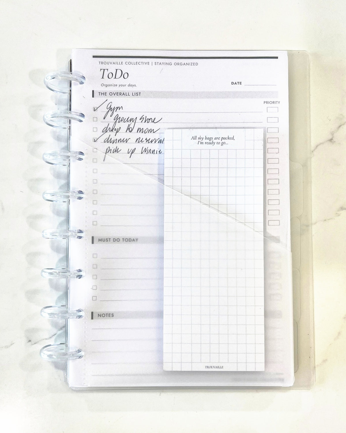 Frosted notebook pocket holding a grid note pad inside a clear half letter discbound planner with 8 discs and a handwritten To Do page