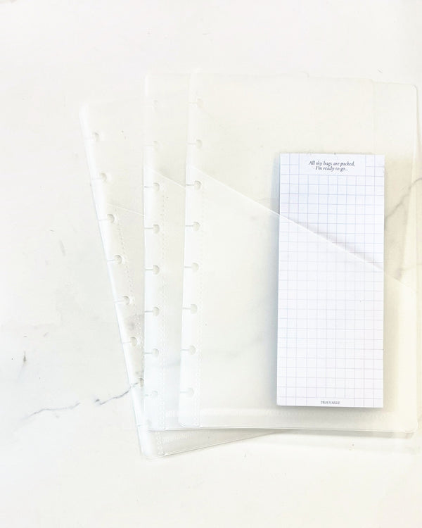 Set of three frosted half letter discbound notebook pockets on white marble, one holding a grid note pad