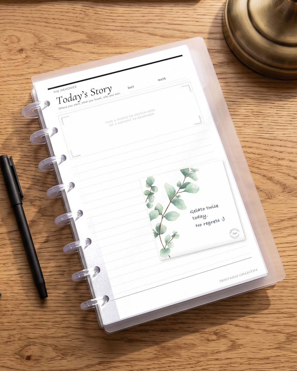 A Greenery sticky note stuck on a planner page in a half letter discbound planner on an oak desk, with handwritten notes
