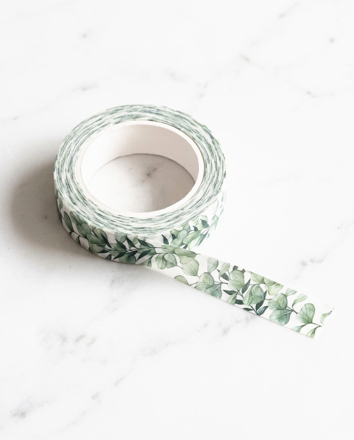 Roll of Greenery washi tape with a strip pulled out, on white marble