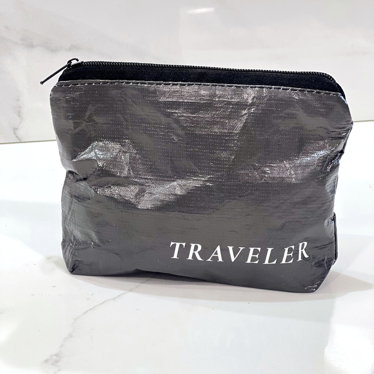 Ink charcoal Mini zip pouch sitting on a white marble counter
