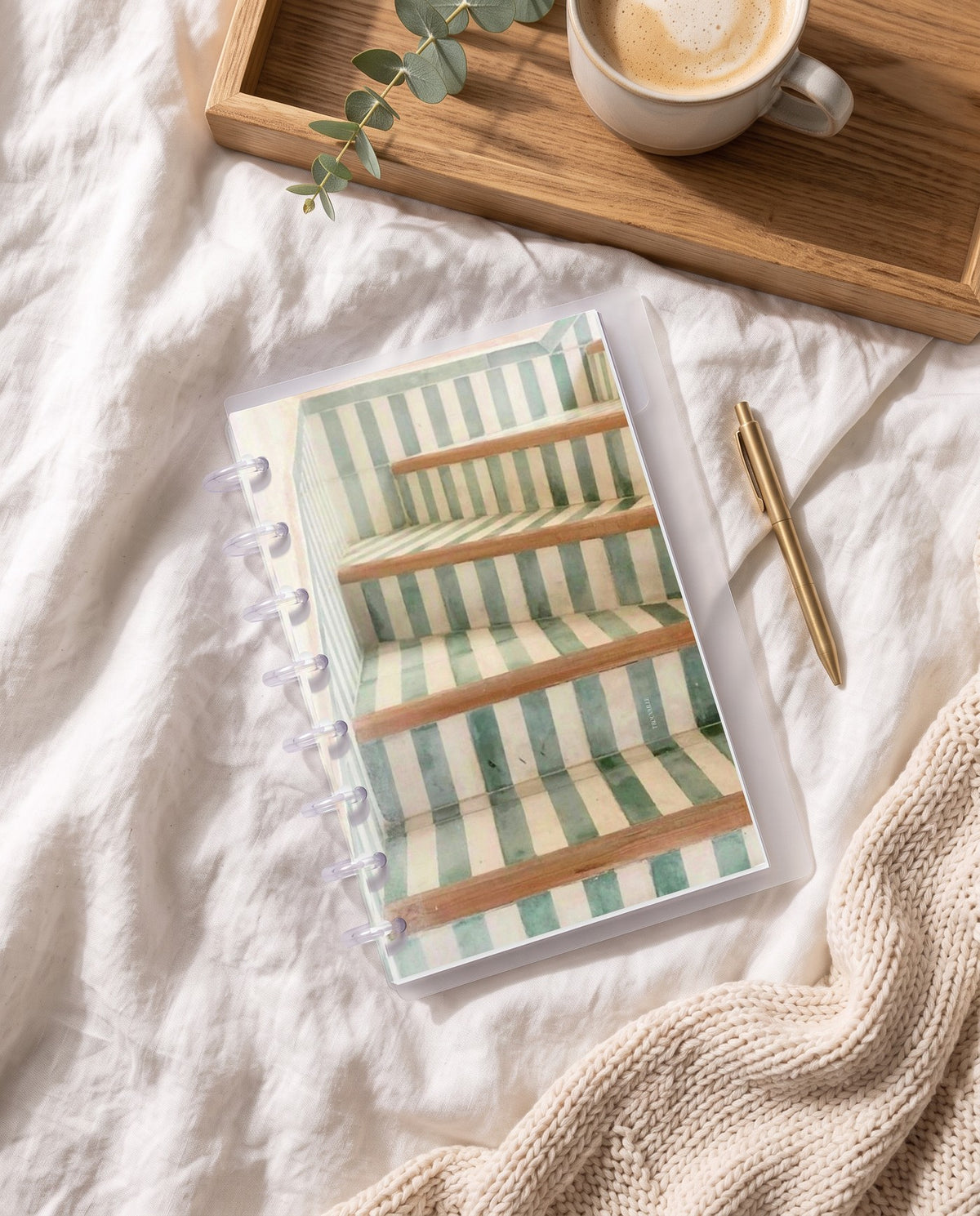 Stairs cardstock planner dashboard inside a clear half letter discbound planner with 8 discs on white linen bedding with a breakfast tray