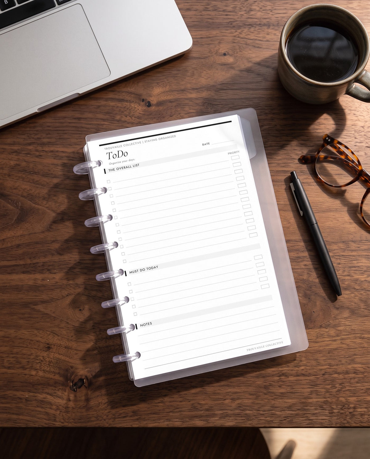 To Do planner insert inside a clear half letter discbound planner with 8 discs on a walnut desk with coffee, a laptop and reading glasses