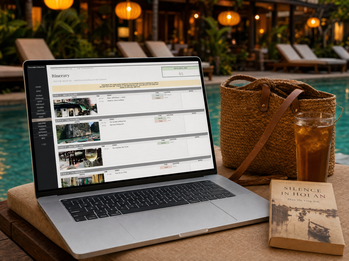 The Traveler Edit itinerary open on a laptop by a Hoi An resort pool in Vietnam, with a straw tote and iced tea nearby