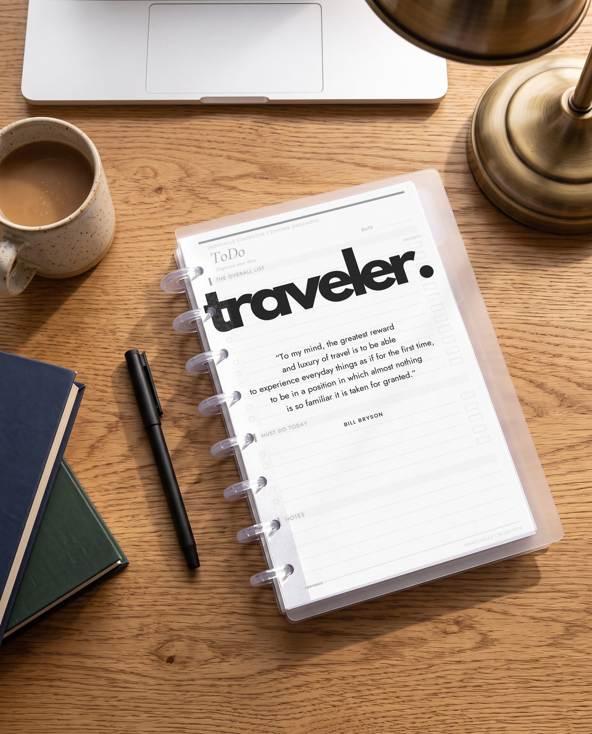 Traveler frosted planner dashboard inside a clear half letter discbound planner with 8 discs on an oak desk with coffee and books