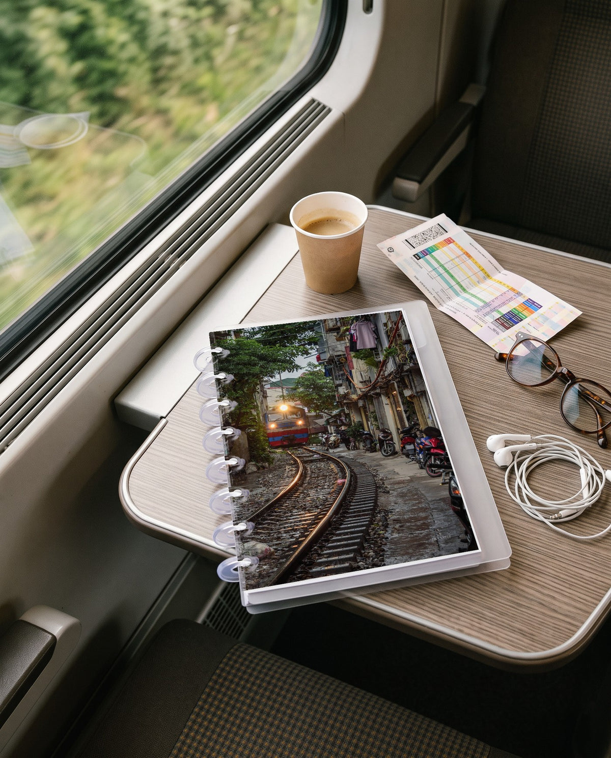 Vietnam Train cardstock planner dashboard inside a clear half letter discbound planner with 8 discs on a train window table