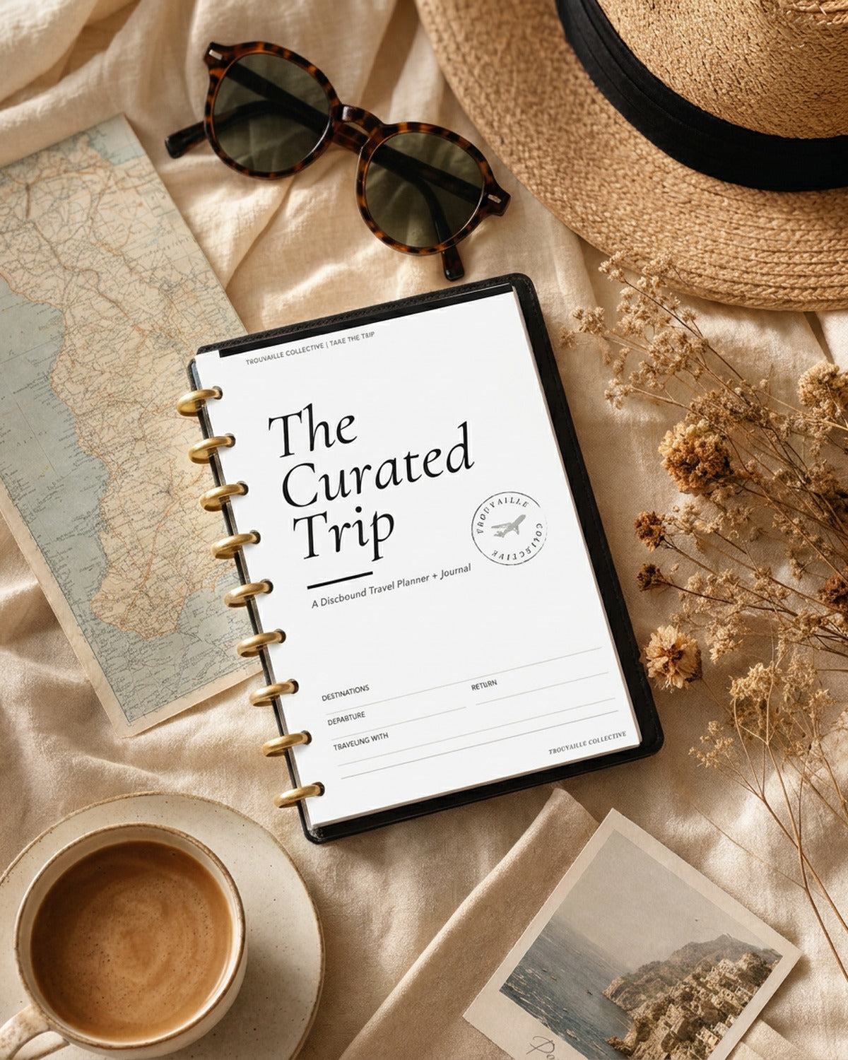 The Curated Trip travel journal on linen with a map, sun hat and coffee